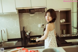 A woman sitting at a kitchen counter eating a piece of food.