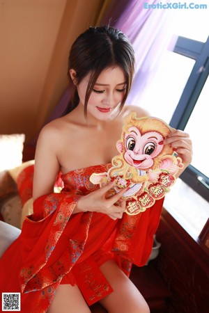 A woman in a red lingerie sitting on a bed.