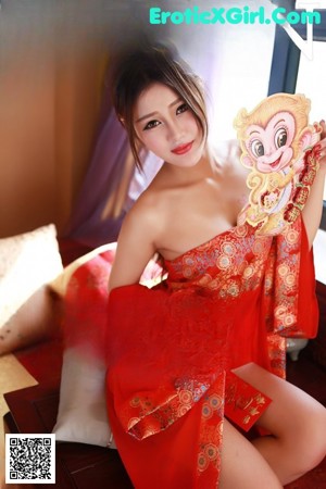 A woman in a red lingerie sitting on a bed.