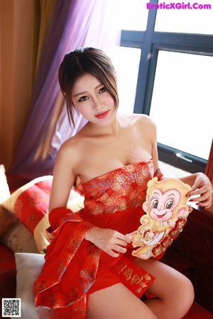 A woman in a red lingerie sitting on a bed.