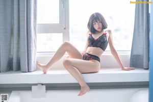 A woman in a black lingerie sitting in a bathtub.
