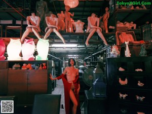 A naked woman standing in a room with a chandelier.