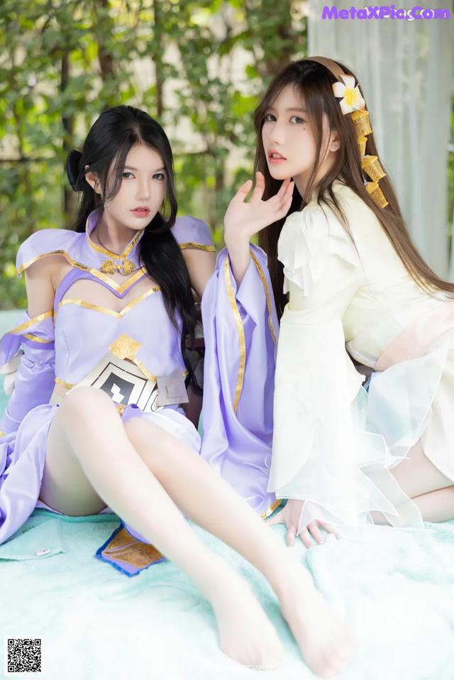 A couple of women sitting on top of a bed.
