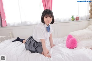 A woman laying on a bed holding a pink teddy bear.