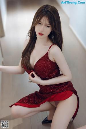 A woman in a red dress sitting on a kitchen counter.