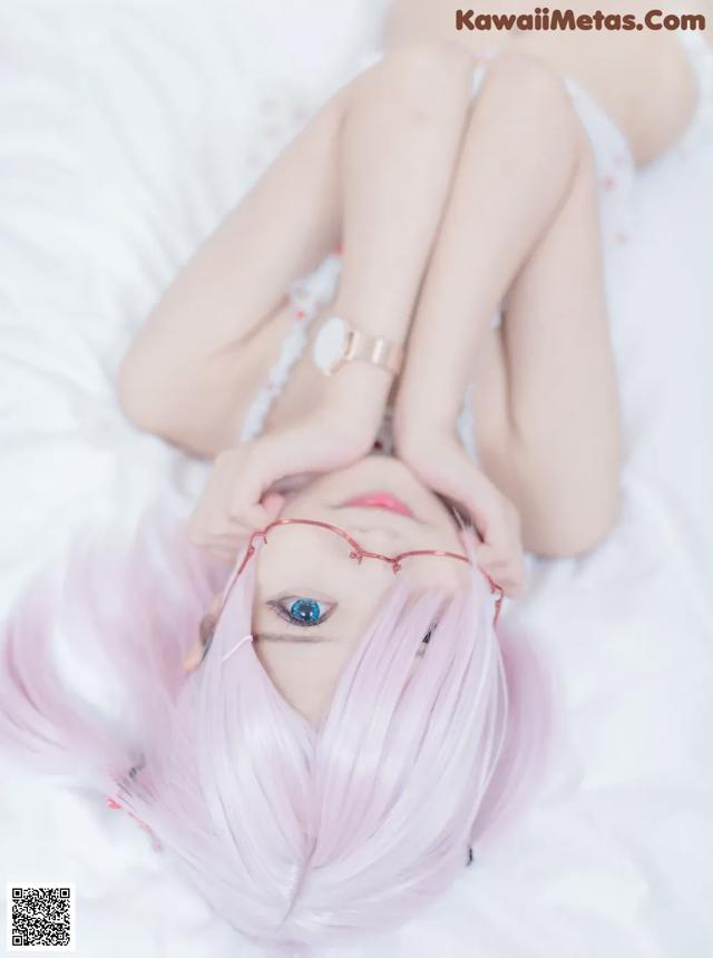 A woman with pink hair laying on a bed.