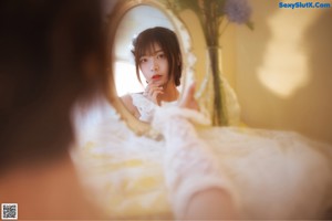 A woman in a white dress looking out of a window.