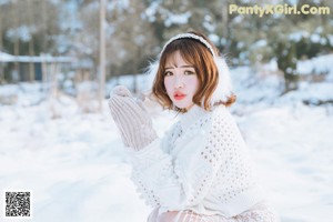 A woman wearing a white sweater and a headband in the snow.