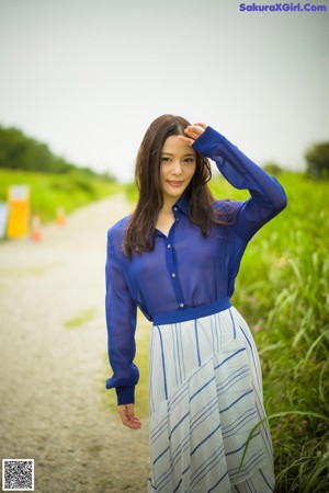 A woman in a white shirt and blue skirt posing for a picture.