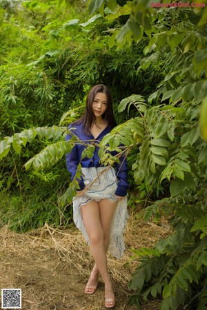 A woman in a white shirt and blue skirt posing for a picture.