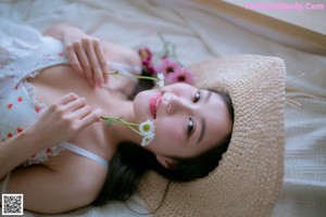 A woman sitting on a window sill holding a flower.
