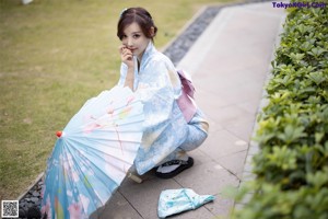 A woman in a blue and pink kimono posing for a picture.