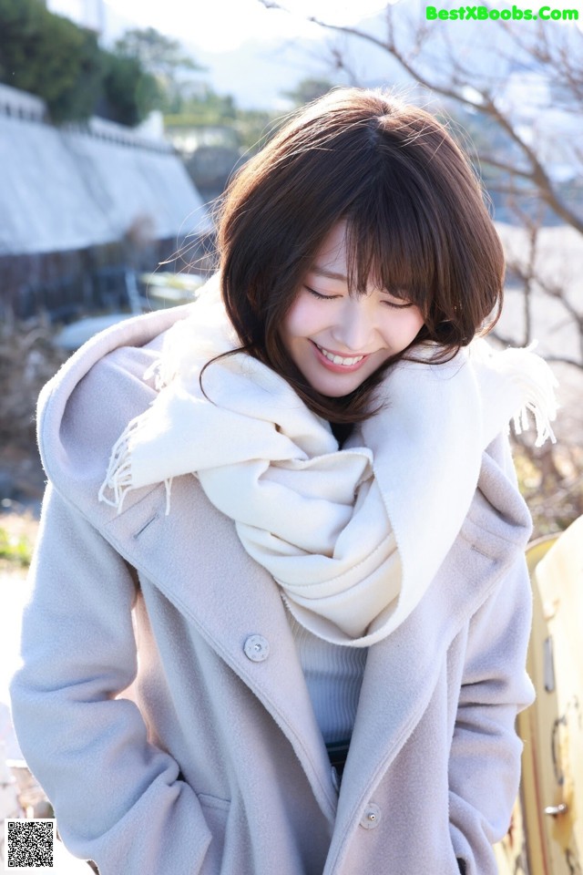 A woman wearing a gray coat and a white scarf.