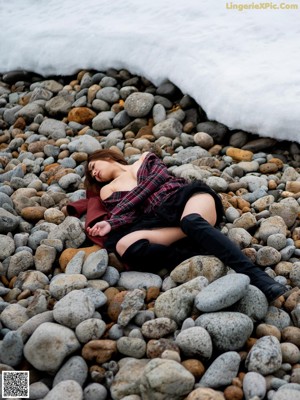 A woman sitting on a rock by the water.