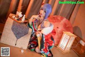 A woman with blue hair sitting on a bed.