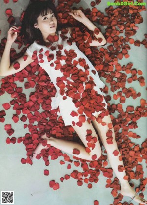 A woman holding a red rose in front of her face.