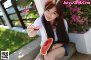 A woman sitting on the floor drinking orange juice.