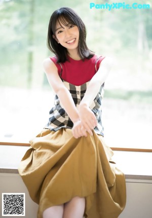 A woman in a black and white checkered dress smiles at the camera.