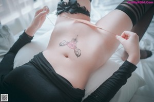 A woman in a black shirt and black stockings laying on a bed.