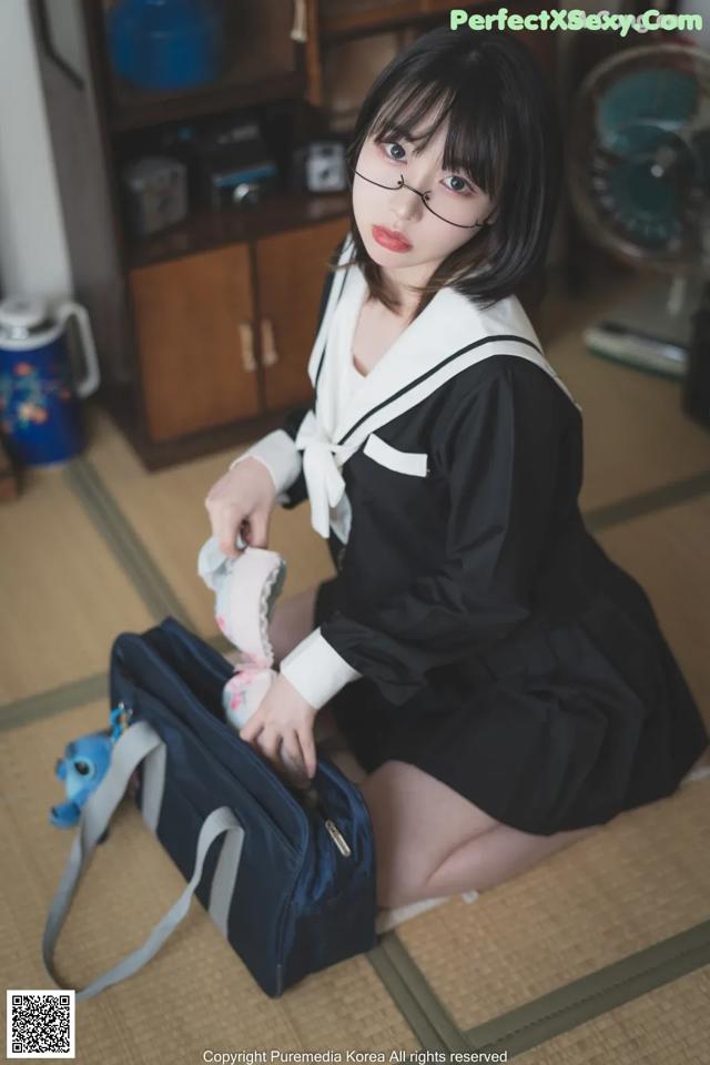 A woman in a school uniform sitting on the floor.