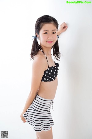 A woman in a black and white polka dot bikini top and striped skirt.