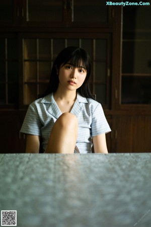 A woman sitting at a table with her hand on her chin.