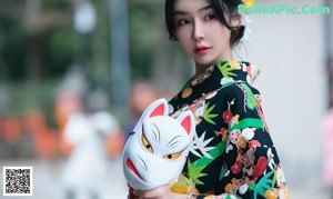 A woman in a kimono standing in front of a pagoda.