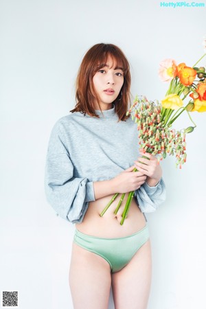 A woman in a green bikini holding a bunch of bamboo.