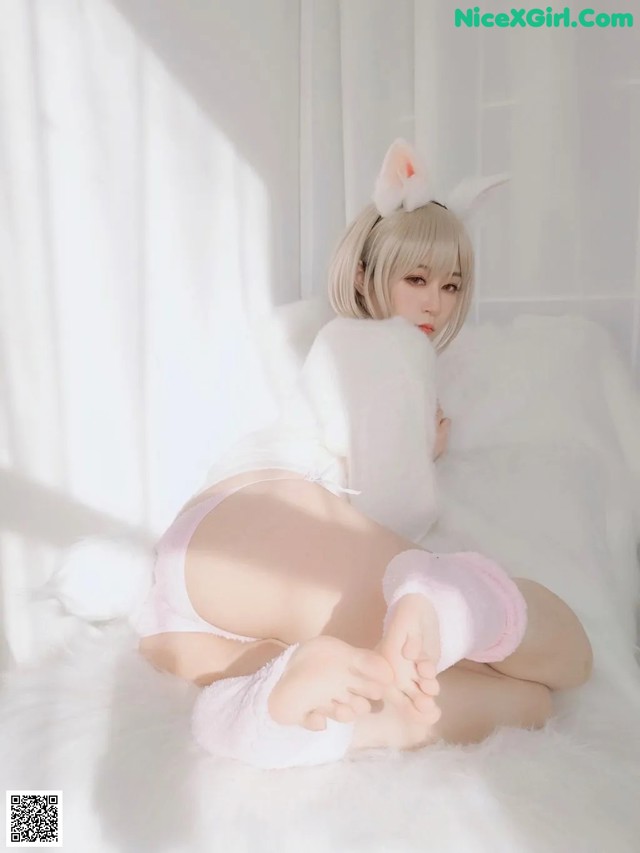 A woman in a bunny costume laying on a bed.