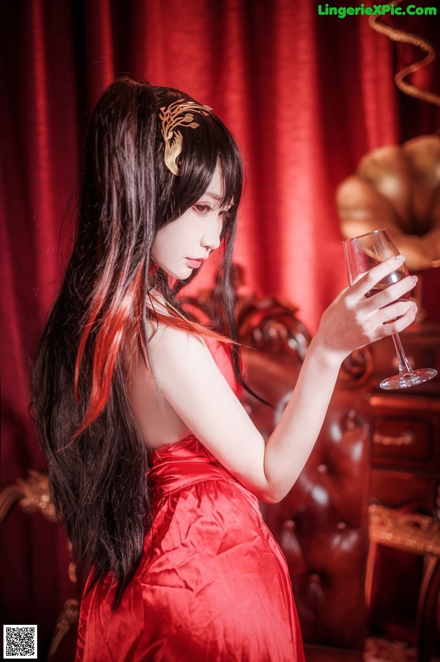 A woman in a red dress holding a glass of wine.