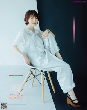 A woman in a white jumpsuit is posing for a magazine.