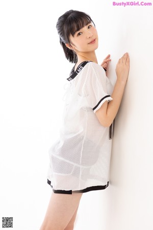 A woman in a white shirt and black shorts holding a bunch of balloons.