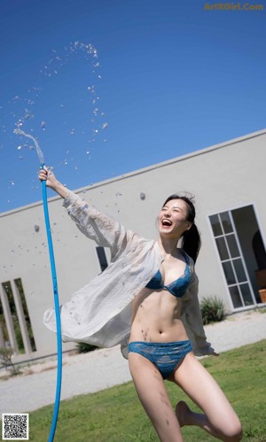 A woman in a blue bra and panties leaning against a window.