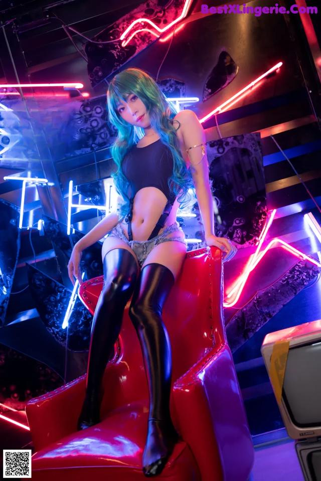 A woman sitting on a red chair in a neon room.