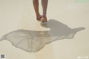 A naked woman standing in the sand on a beach.