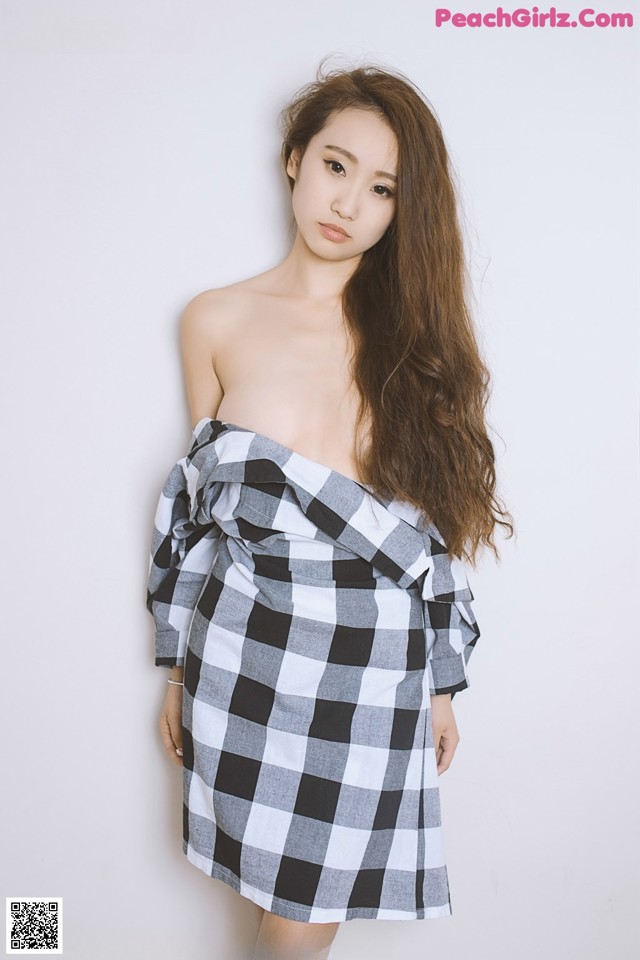 A woman in a black and white checkered dress posing for a picture.