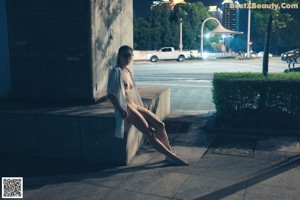 A naked woman standing on top of a building next to a window.