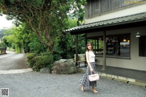 A woman in a kimono standing in front of a window.