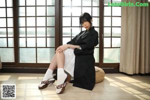 A woman in a kimono sitting on the floor in front of a window.