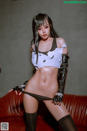 A naked woman in a latex outfit posing on a red couch.
